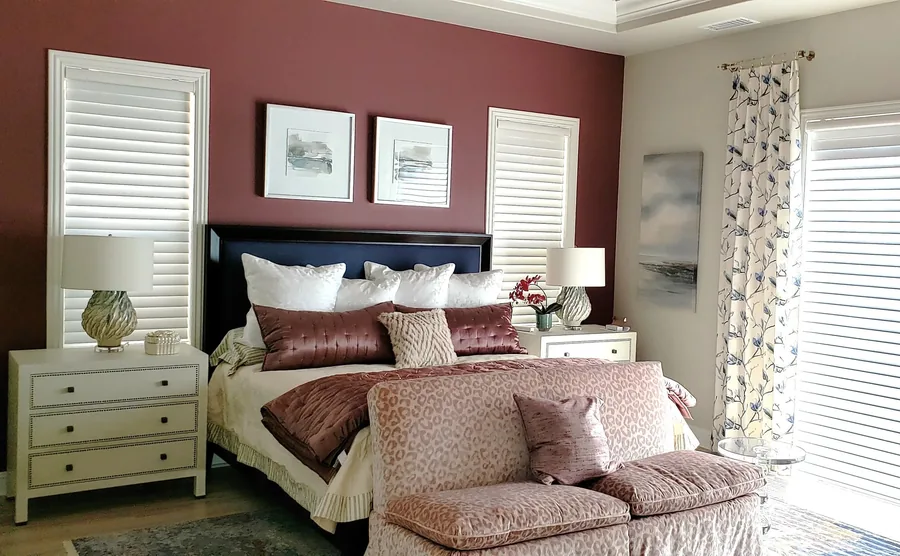 Primary bedroom with a terracotta accent wall, upholstered bed, layered pillows and framed art.