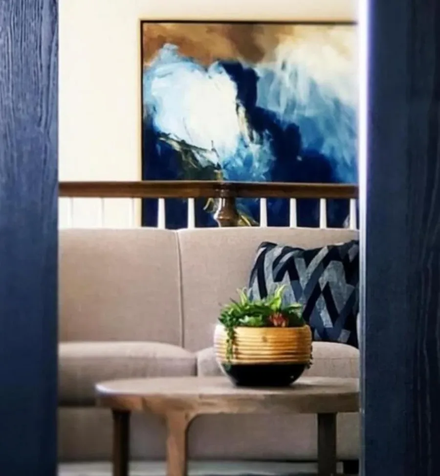 Navy-paneled reading nook with a large blue abstract painting and a modern lounge chair.