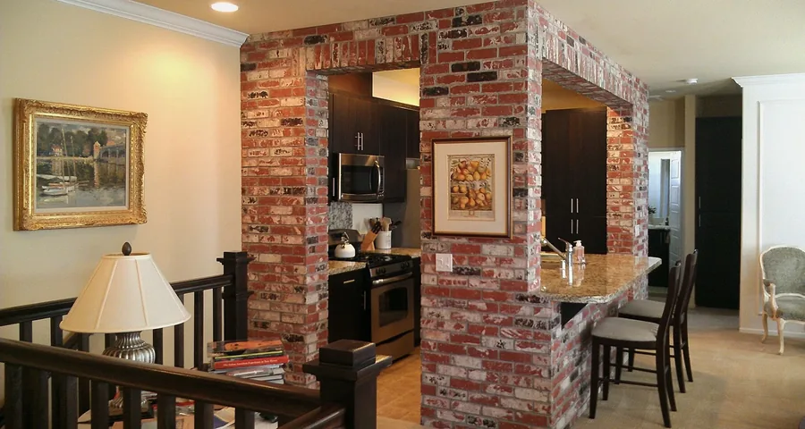 Kitchen and dining area framed by a reclaimed exposed-brick archway with warm cabinetry.