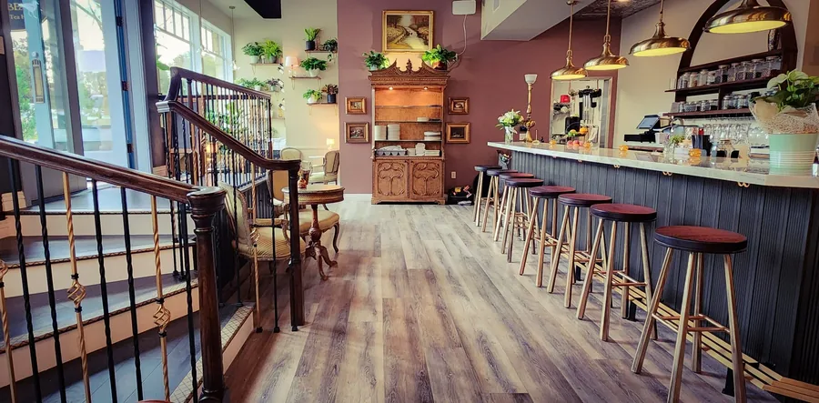 Corbeaux café interior showing the bar, bar stools, wood floors and open stair to a mezzanine.