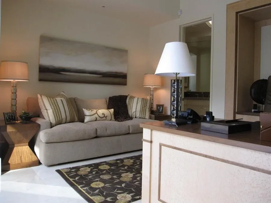 Living room layered in warm neutral tones with a sectional, matching table lamps and abstract art.