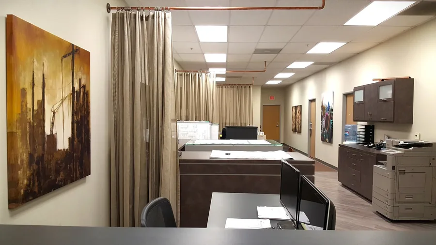 Executive office with a custom desk, layered lighting and framed cityscape artwork.