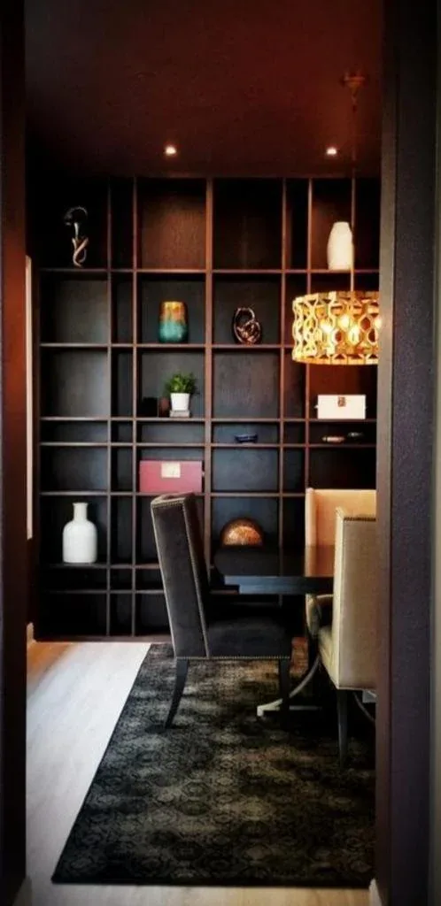 Custom home library with moody backlit shelving and a quiet reading corner.