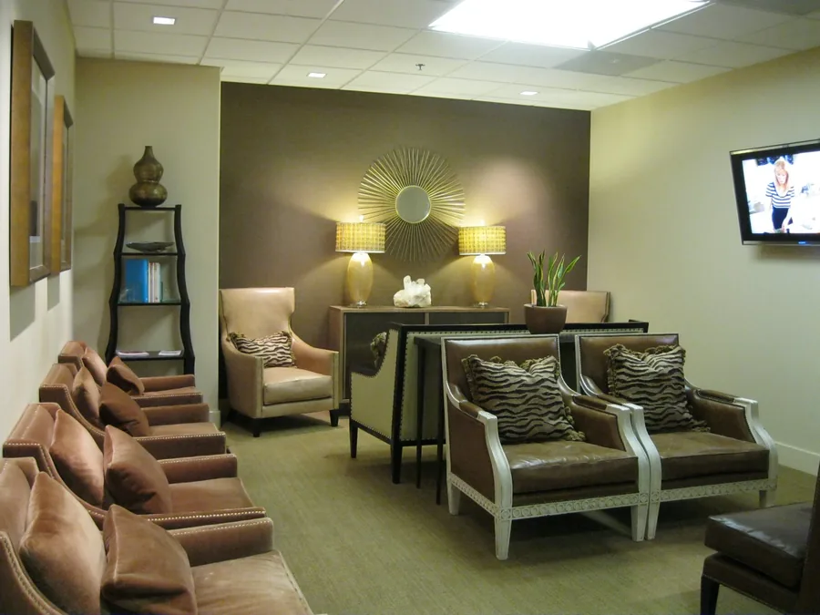 Wellness reception and waiting area in sage-green tones with walnut accents and lounge chairs.