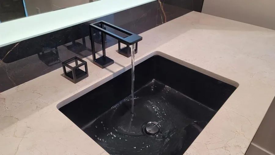 Minimalist dark quartz undermount sink with a waterfall-edge counter.