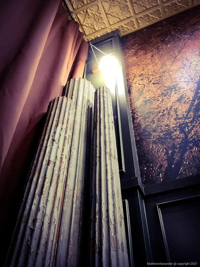 Dramatic pooling silk drapery in a corner against a hand-finished antiqued metallic wall.