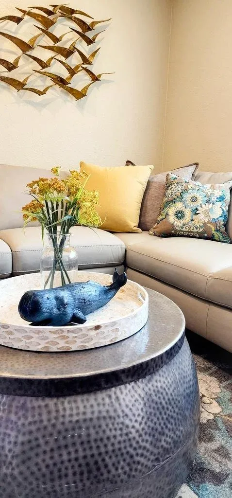 Living room detail with a hammered drum coffee table and a gilded ribbon wall sculpture.