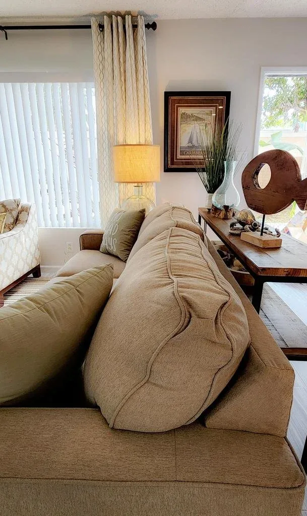 Living room with a neutral sectional, styled console table and a sculptural accent piece.