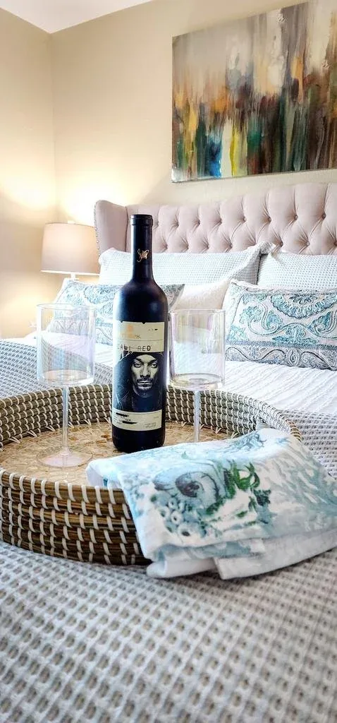 Coastal-styled bedroom with a tufted headboard, patterned bedding and a welcome tray.