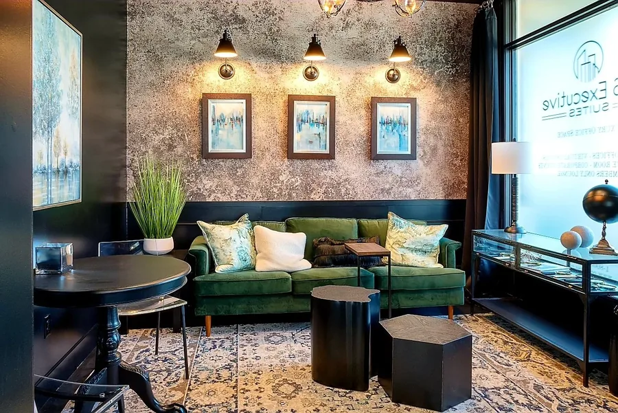 Commercial lounge with an emerald-green velvet sofa, textured wall and framed gallery.