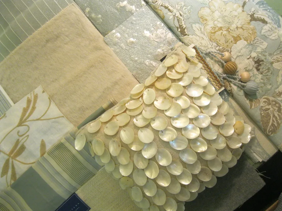 Flat-lay of design materials including capiz shell, linen swatches and layered natural textures.