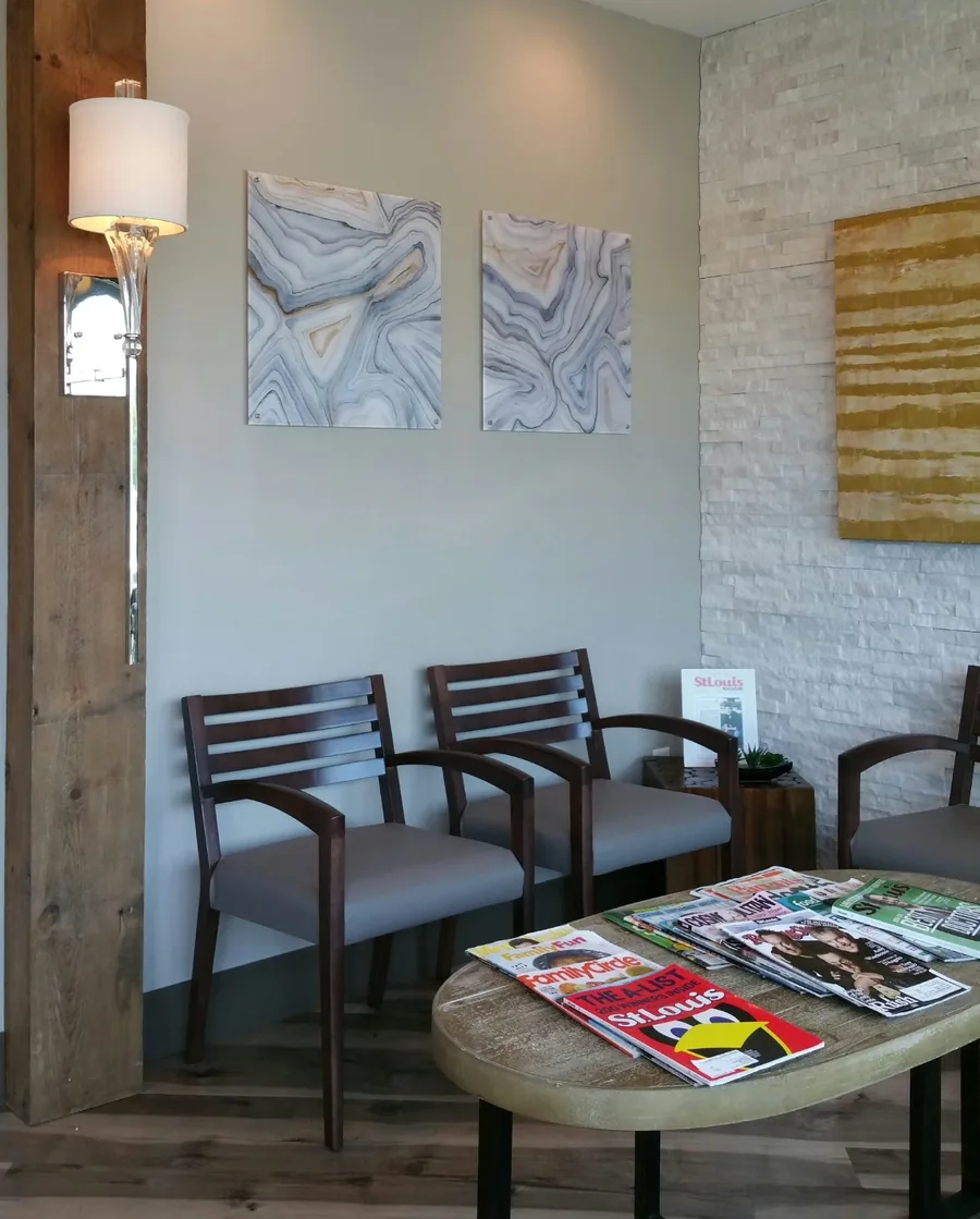 Professional waiting room with upholstered chairs, layered lighting and framed artwork.