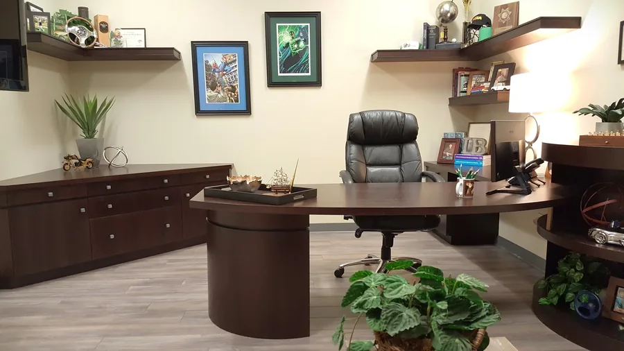 Executive office with a custom wood desk, floating shelves and framed art.