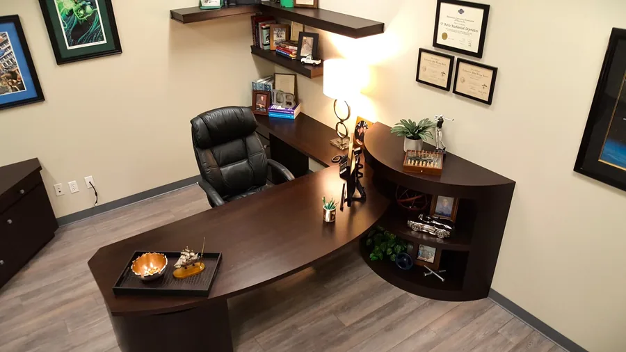 Executive office suite with a curved wood workstation and warm task lighting.