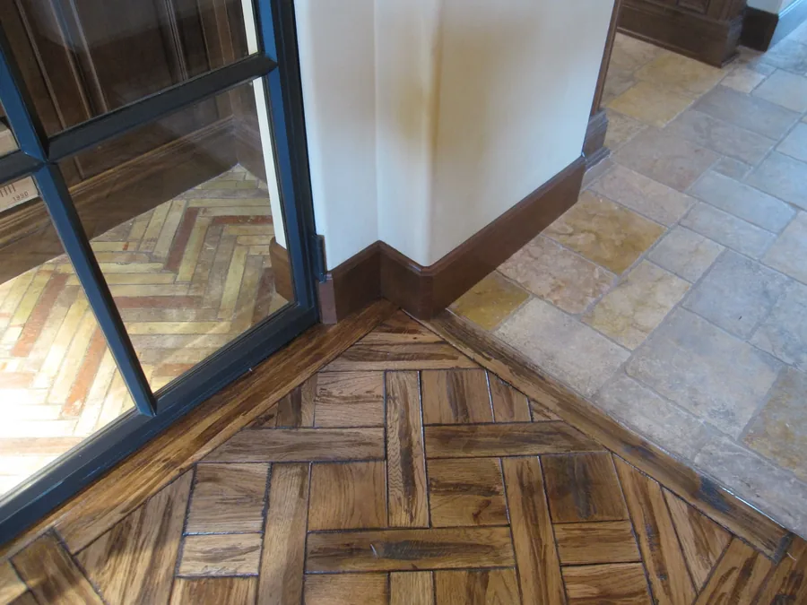 Detail of a herringbone wood floor inset within a travertine tile border.