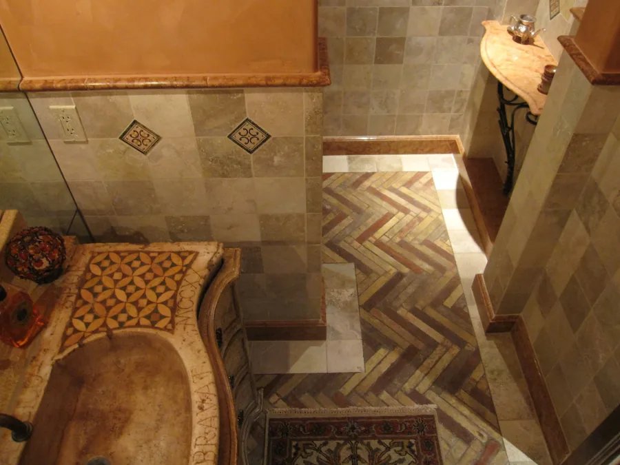Inlaid travertine and wood floor with a decorative medallion at the base of a staircase.