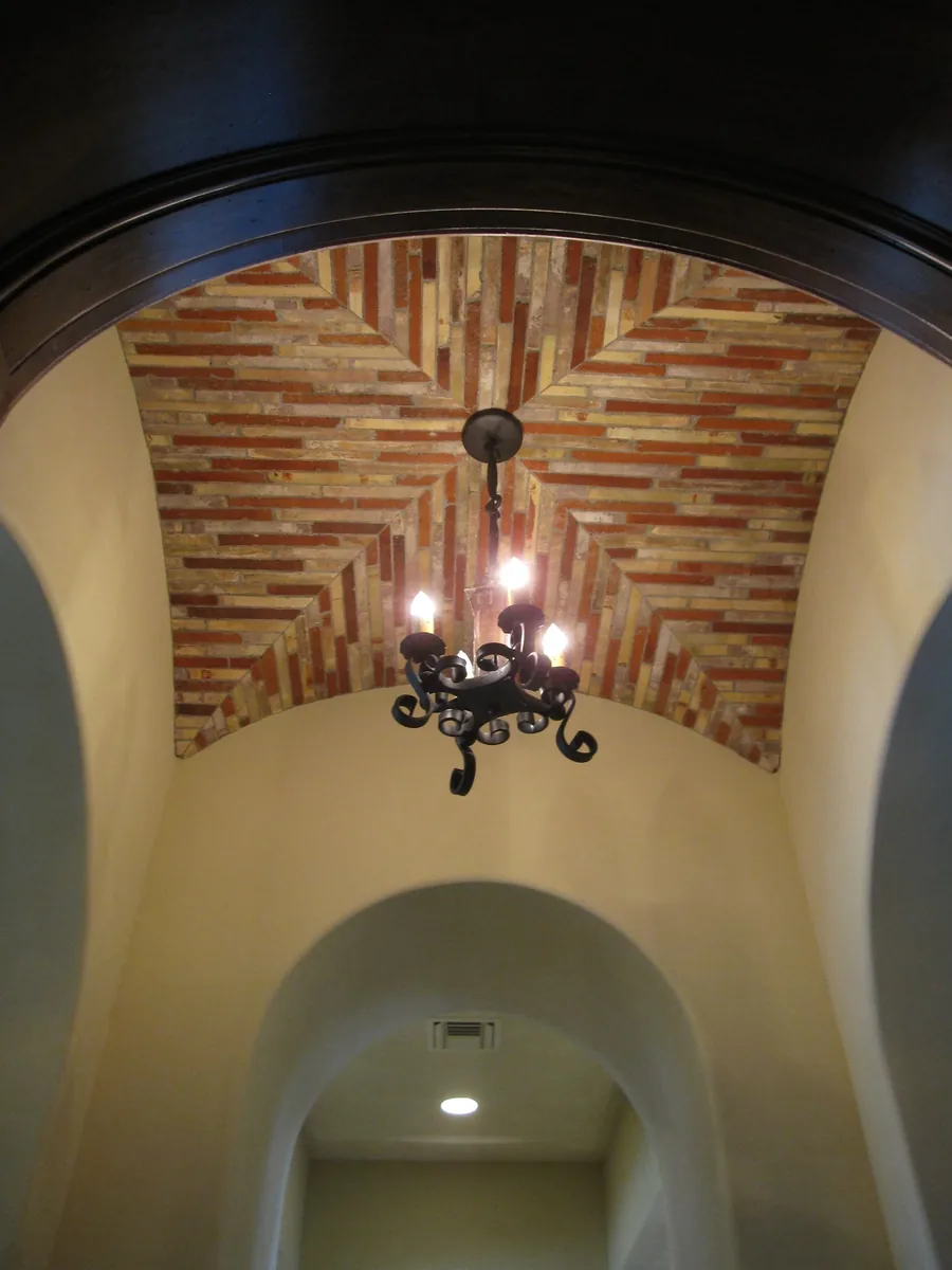 Architectural domed brick ceiling with an ornate wrought-iron chandelier.