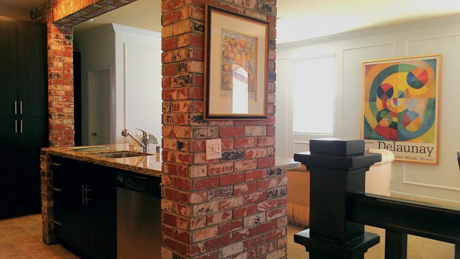 Butler's pantry and bar with exposed brick, custom dark cabinetry and framed art.